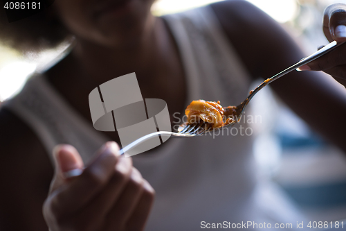 Image of a young African American woman eating pasta