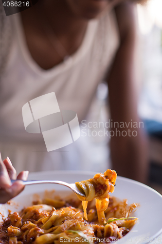 Image of a young African American woman eating pasta