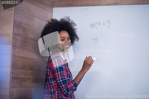 Image of African American woman writing on a chalkboard in a modern offic