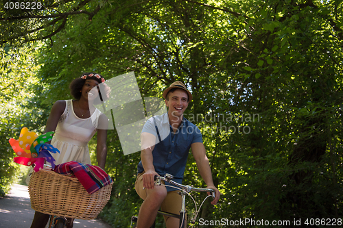 Image of Young multiethnic couple having a bike ride in nature