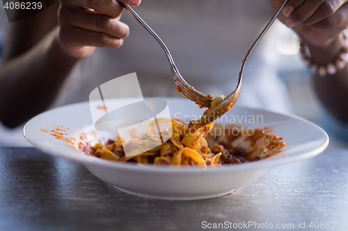 Image of a young African American woman eating pasta