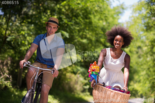 Image of Young multiethnic couple having a bike ride in nature