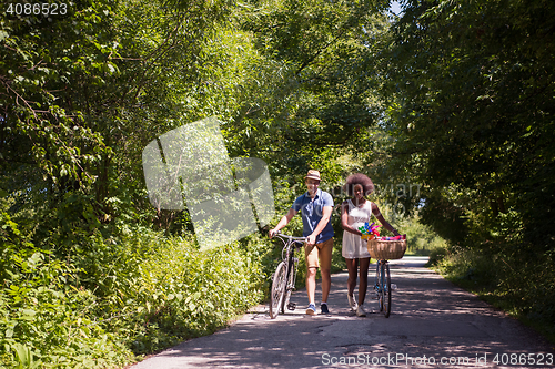 Image of Young multiethnic couple having a bike ride in nature