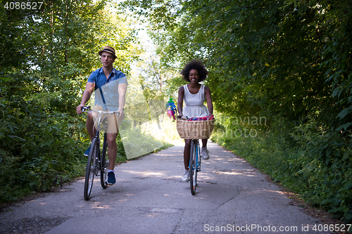 Image of Young multiethnic couple having a bike ride in nature