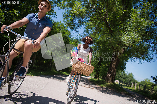 Image of Young multiethnic couple having a bike ride in nature