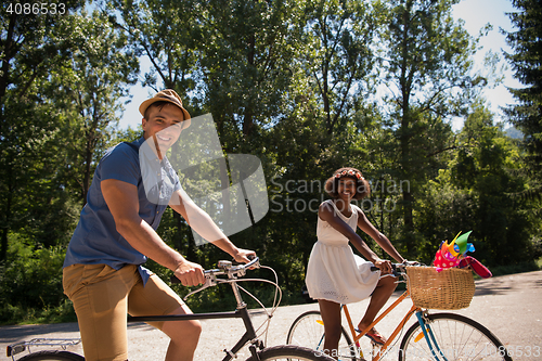 Image of Young multiethnic couple having a bike ride in nature