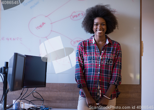 Image of African American woman writing on a chalkboard in a modern offic
