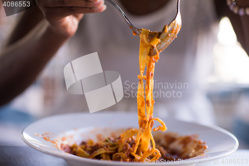 Image of a young African American woman eating pasta