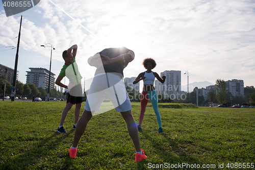 Image of multiethnic group of people stretching in city park
