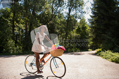 Image of pretty young african american woman riding a bike in forest