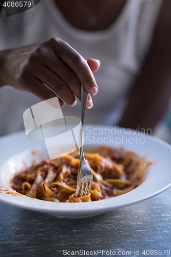 Image of a young African American woman eating pasta