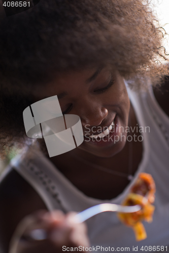 Image of a young African American woman eating pasta