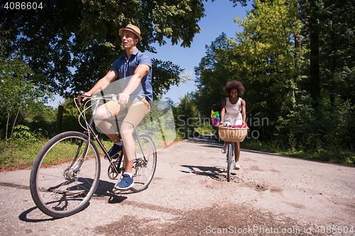 Image of Young multiethnic couple having a bike ride in nature