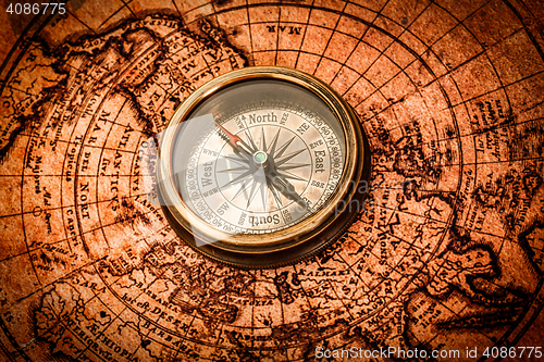 Image of Vintage compass lies on an ancient world map.