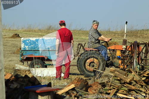 Image of rural men work with tractor with trailer