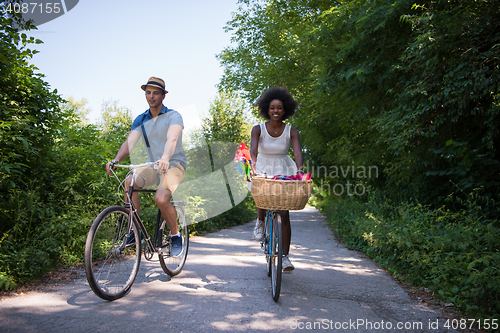 Image of Young multiethnic couple having a bike ride in nature