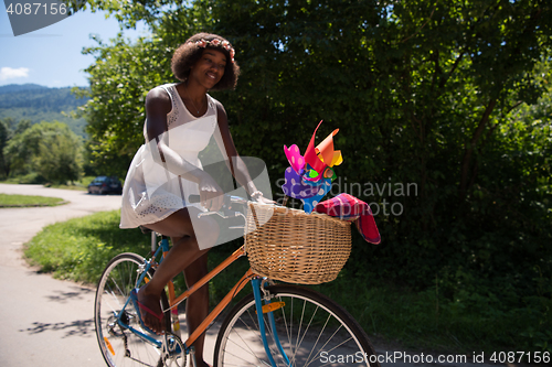 Image of pretty young african american woman riding a bike in forest