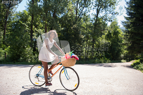 Image of pretty young african american woman riding a bike in forest