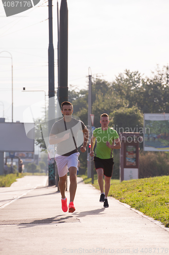 Image of Two young men jogging through the city