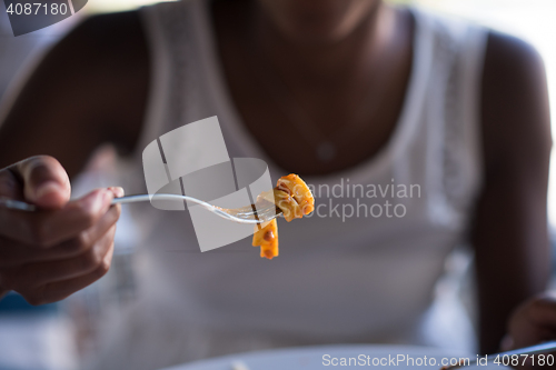 Image of a young African American woman eating pasta