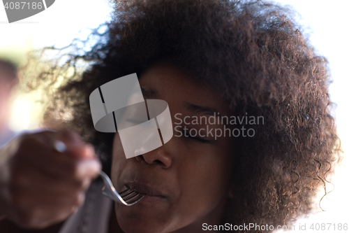 Image of a young African American woman eating pasta