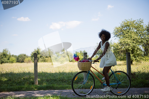 Image of pretty young african american woman riding a bike in forest