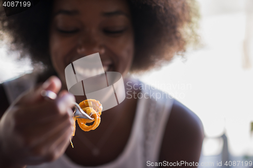 Image of a young African American woman eating pasta