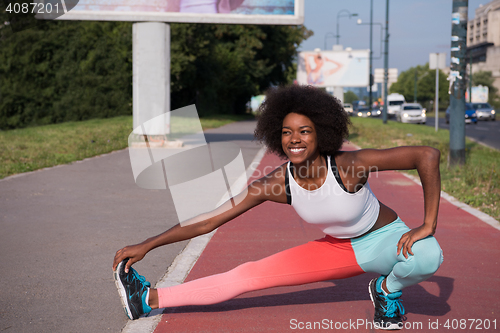 Image of Portrait of sporty young african american woman stretching outdo