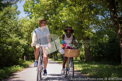 Image of Young multiethnic couple having a bike ride in nature