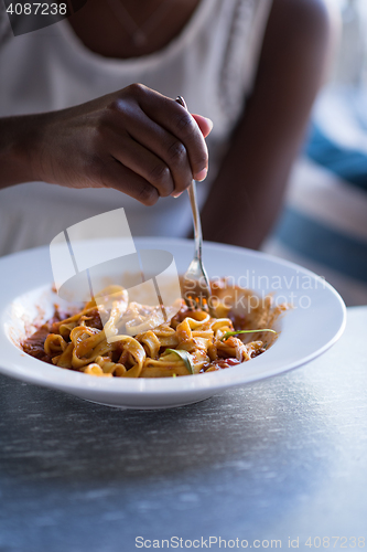 Image of a young African American woman eating pasta