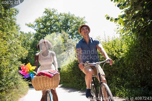 Image of Young multiethnic couple having a bike ride in nature