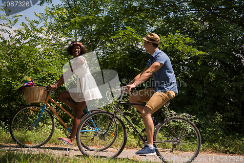 Image of Young multiethnic couple having a bike ride in nature