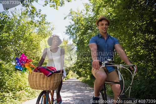 Image of Young multiethnic couple having a bike ride in nature