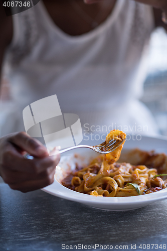 Image of a young African American woman eating pasta