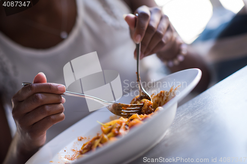 Image of a young African American woman eating pasta