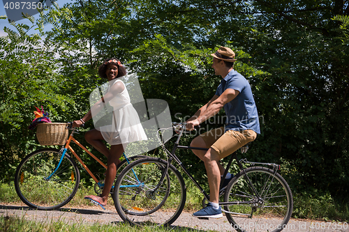 Image of Young multiethnic couple having a bike ride in nature