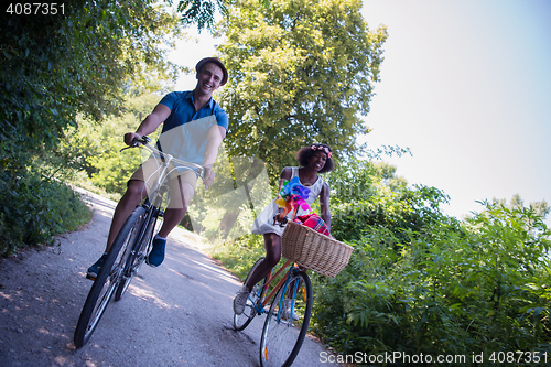 Image of Young multiethnic couple having a bike ride in nature