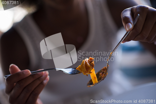 Image of a young African American woman eating pasta