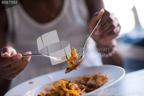 Image of a young African American woman eating pasta