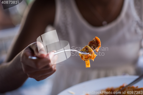 Image of a young African American woman eating pasta