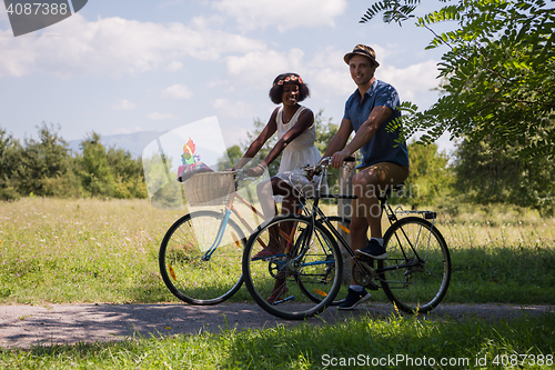 Image of Young multiethnic couple having a bike ride in nature