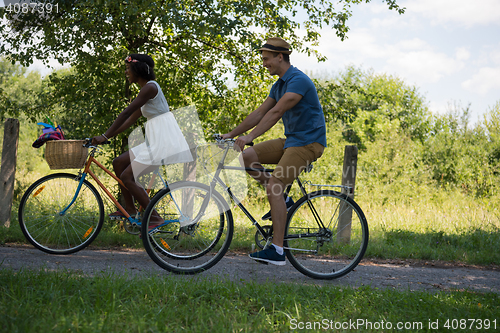 Image of Young multiethnic couple having a bike ride in nature