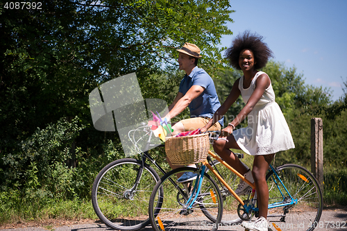 Image of Young multiethnic couple having a bike ride in nature