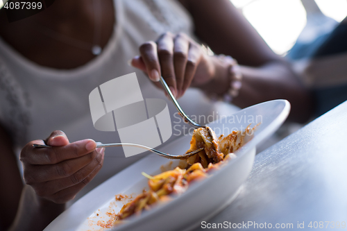 Image of a young African American woman eating pasta