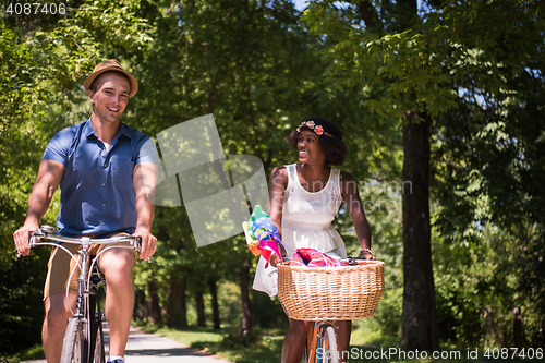 Image of Young multiethnic couple having a bike ride in nature