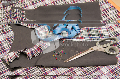 Image of Top view of the child billet school dress lying on the table with sewing accessories