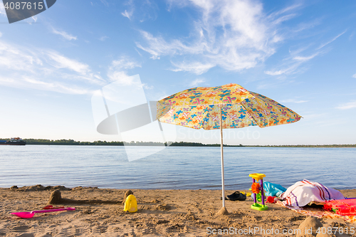 Image of Parasol on the river bank, under which the scattered items and toys