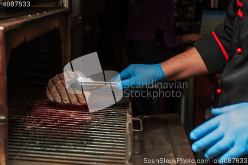 Image of Chef roasts meat steak