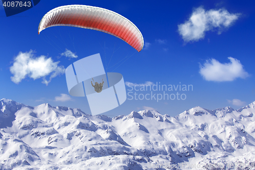 Image of Paragliding over the mountains on background of blue sky and whi