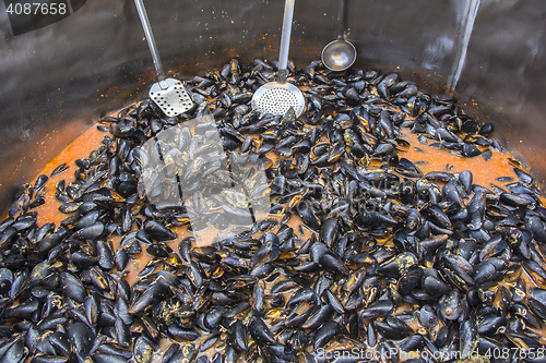 Image of Mussels in red sauce in big cauldron on a Street market
